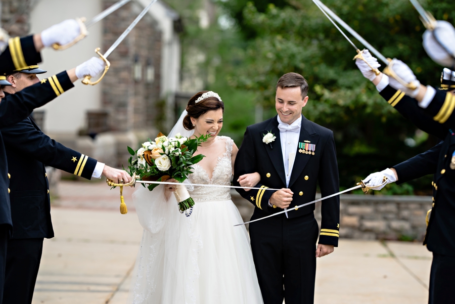 A Navy couple stopped at the entrance of their sword arch.